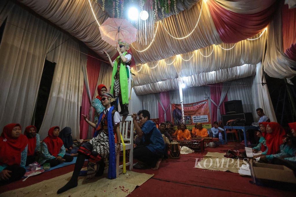 Noni Serli Lestari (13) menari di atas kursi saat tampil sebagai sintren dalam sebuah pertunjukan seni sintren bersama Paguyuban Kesenian Sintren Laras Kinasih di Desa Tlaga, Kecamatan Gumelar, Kabupaten Banyumas, Jumat (25/3/2022) malam.