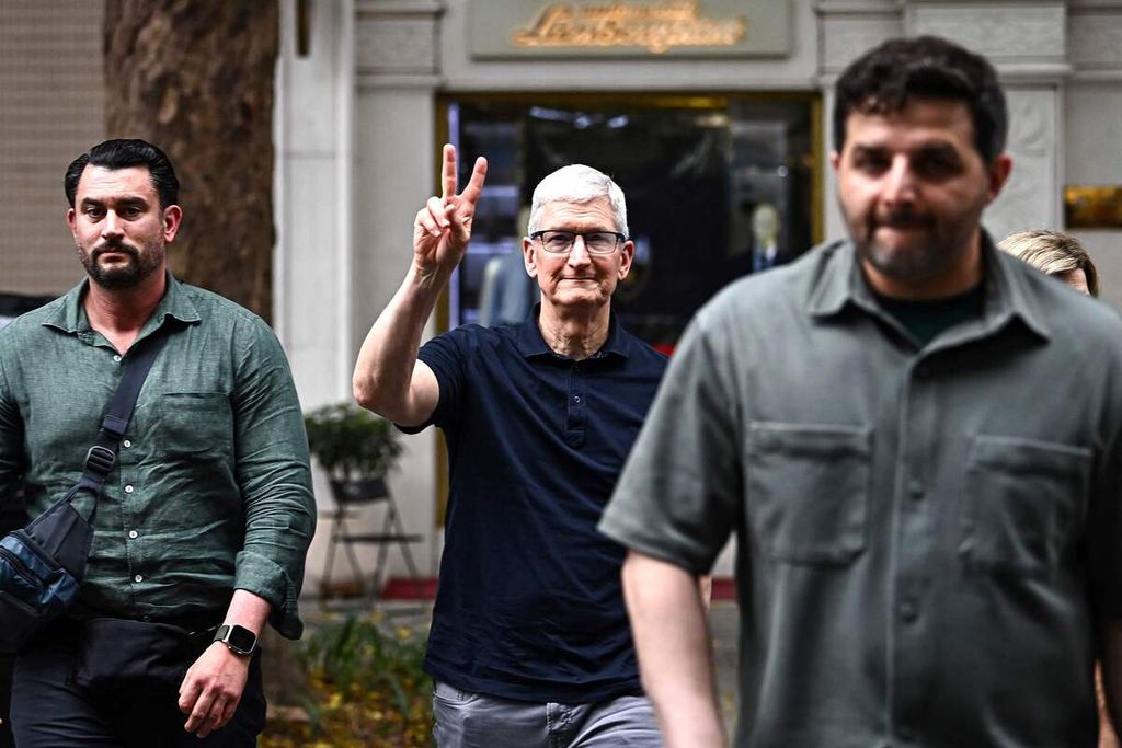 CEO Apple Tim Cook menunjukkan gerak isyaratnya saat menyeberang jalan di kawasan Hanoi saat berkunjung ke Vietnam, Senin (15/4/2024).