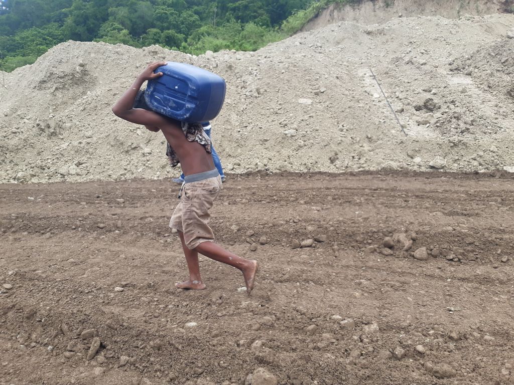 Seorang remaja memikul jeriken berisi bahan bakar melewati lokasi longsor Kelurahan Takari, Kabupaten Kupang, Nusa Tenggara Timur, pada Senin (20/2/2023). Longsor menghambat mobilisasi logistik termasuk bahan bakar.