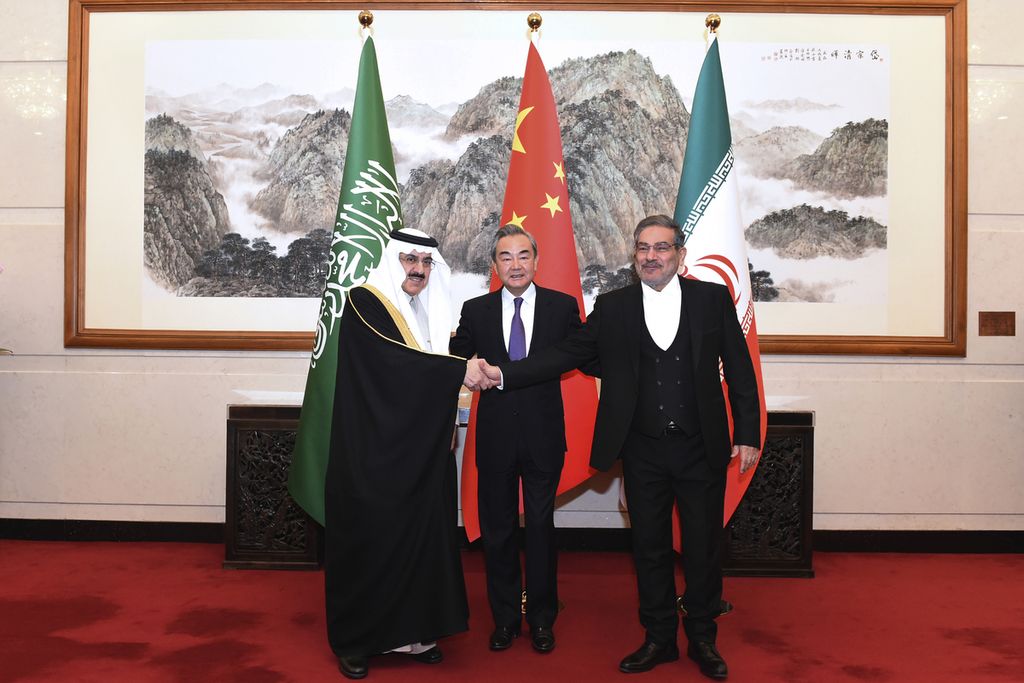  Foto yang dirilis kantor berita China, Xinhua, ini menunjukkan Sekretaris Dewan Keamanan Nasional Tertinggi Iran, Ali Shamkhani (kanan), berjabat tangan dengan Penasehat Keamanan Nasional Arab Saudi, Musaad bin Mohammed al-Aiban (kiri), disaksikan diplomat senior China Wang Yi, di Beijing, Sabtu (11/3/2023). 