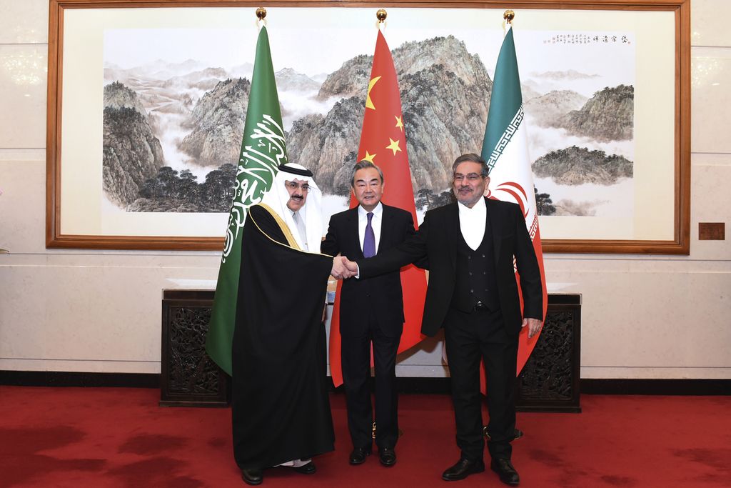 Ali Shamkhani, Sekretaris Dewan Keamanan Nasional Tertinggi Iran (kanan), berjabat tangan dengan Penasihat Dewan Keamanan Nasional Arab Saudi Musaad bin Mohammed al-Aiban (kiri) dan Direktur Kantor Komisi Luar Negeri Komite Pusat Partai Komunis China Wang Yi dalam pertemuan tertutup di Beijing, China, Sabtu (11/3/2023).