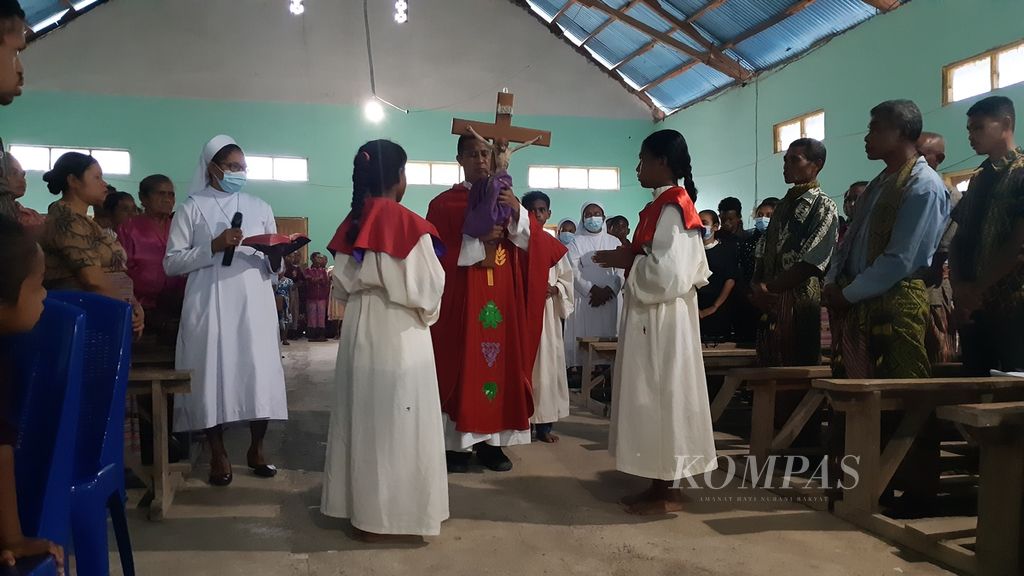 Pastor mengangkat salib Yesus pada Jumat Agung, 15 April 2022. Perayaan umat Katolik itu berlangsung di pedalaman Pulau Timor, tepatnya Kampung Naob, Kabupaten Timor Tengah Utara, Nusa Tenggara Timur.