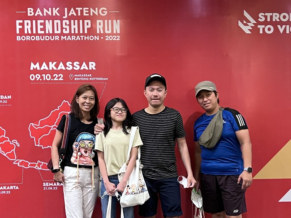 Chloe (13, baju krem) berfoto bersama kedua orangtua dan saudaranya seusai mengambil <i>race pack</i> di Hotel Santika Makassar, Sulawesi Selatan, Sabtu (8/10/2022). Mereka akan meramaikan Friendship Run Makassar yang digelar pada Minggu (9/10/2022).