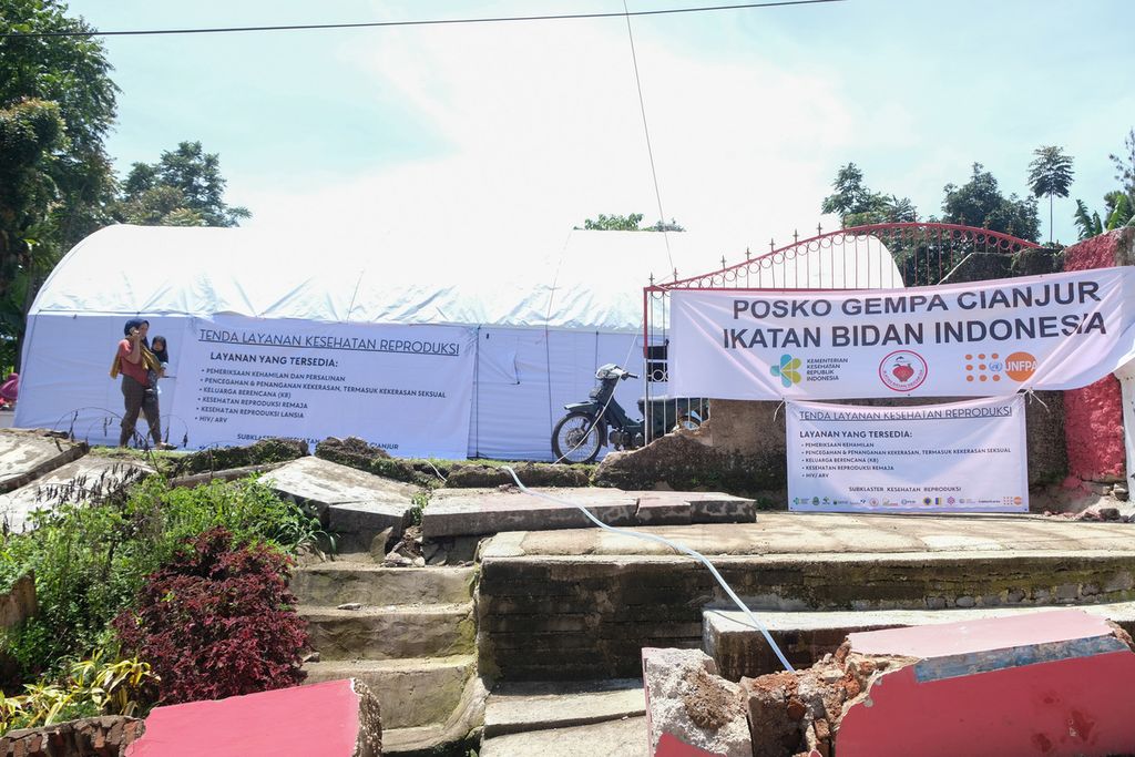 Ibu dan anak melintas di samping Tenda Layanan Kesehatan Reproduksi, Kampung Cariu, Desa Mangunkerta, Kecamatan Cugenang, Kabupaten Cianjur, Jawa Barat, Selasa (29/11/2022). 
