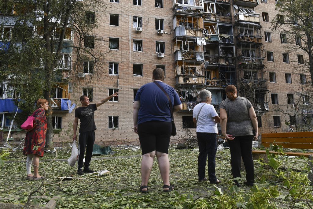 Warga berdiri di luar apartemen di Kursk, Rusia, yang rusak setelah terkena tembakan artileri Ukraina, Minggu (11/8/2024).