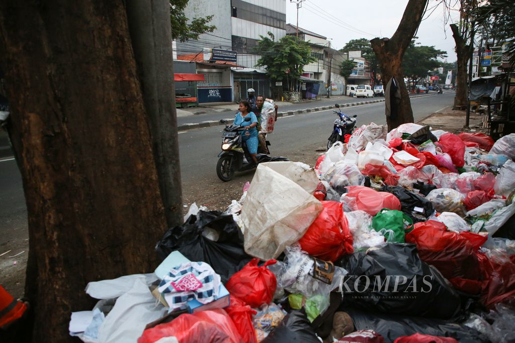 Warga membawa sampah untuk dibuang di pinggir Jalan HOS Cokroaminoto, Larangan, Kota Tangerang, Banten, Selasa (25/4/2023). Selama libur Lebaran, muncul tempat pembuangan sampah liar di pinggir jalan maupun di separator jalan raya.