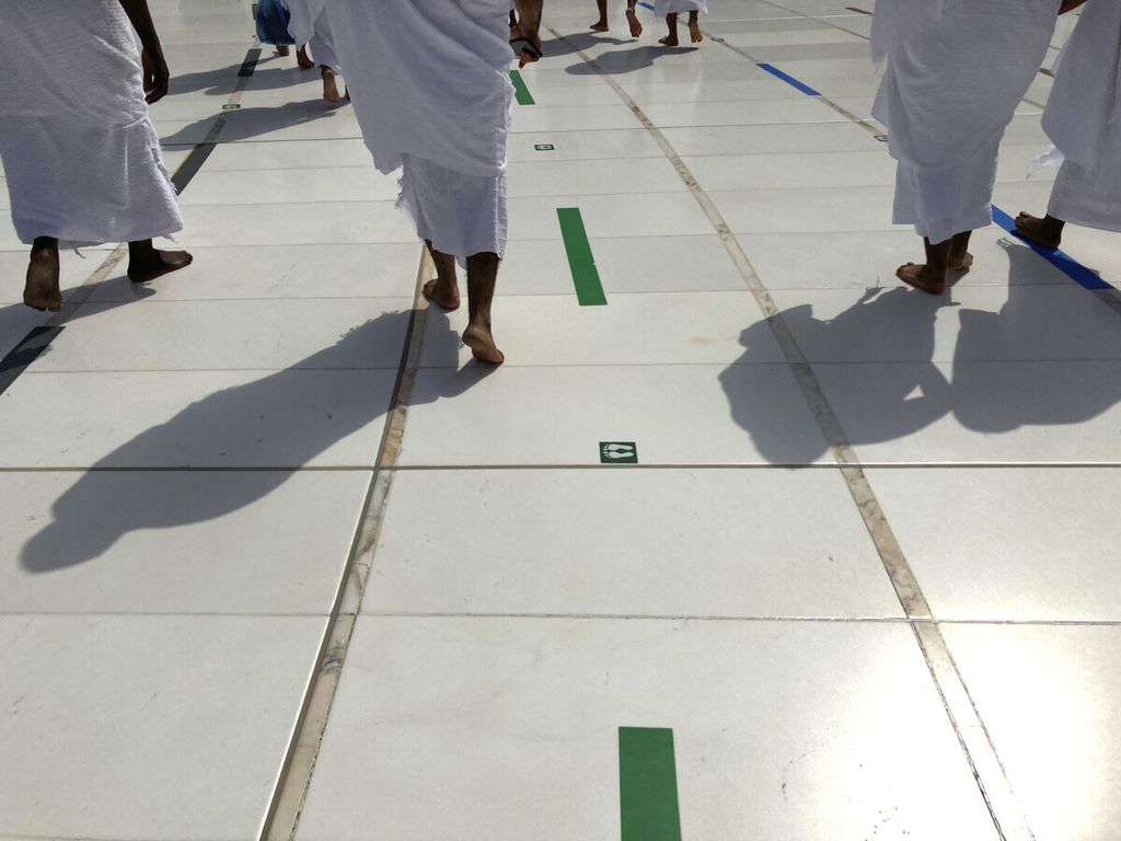 Jemaah umrah mengikuti tanda jaga jarak di lantai saat tawaf di Masjidil Haram, Kota Suci Mekkah, Arab Saudi dalam ibadah Umrah Minggu (30/5/2021). 