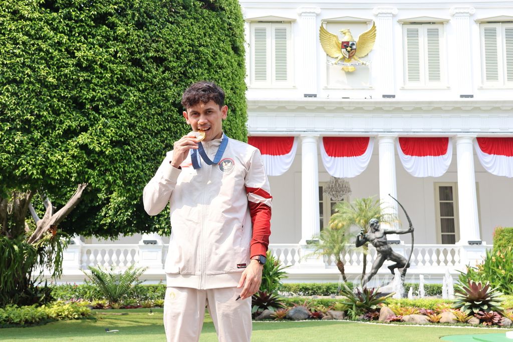 Atlet panjat tebing nomor <i>speed</i> putra Veddriq Leonardo berpose dengan medali emas Olimpiade Paris 2024 di depan Istana Negara, Jakarta, Kamis (15/8/2024).