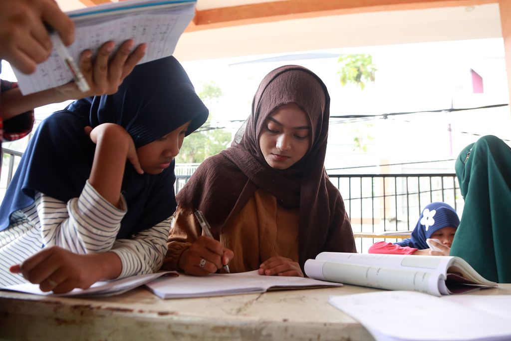 Guru memeriksa tugas dari anak - anak yang mengikuti bimbingan belajar gratis di Taman Baca Masyarakat Kampung Buku, Ciracas, Jakarta Timur, Rabu (21/12/2022). 