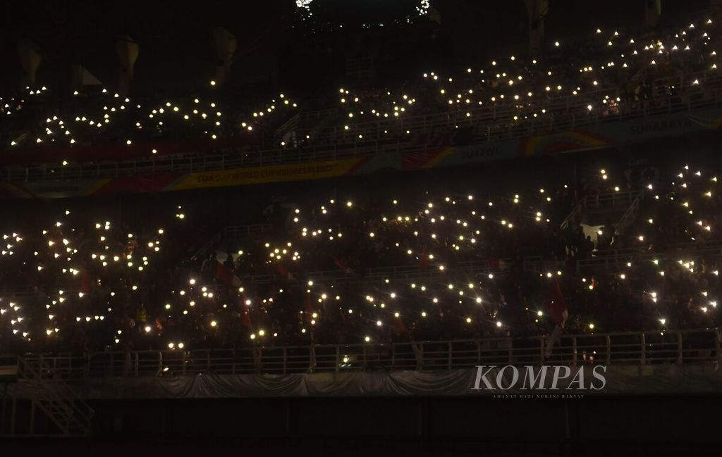 Suporter menyalakan lampu telepon genggam sebelum laga Indonesia melawan Ekuador dalam babak penyisihan Grup A Piala Dunia U-17 2023 di Stadion Gelora Bung Tomo, Surabaya, Jawa Timur, Jumat (10/11/2023). 