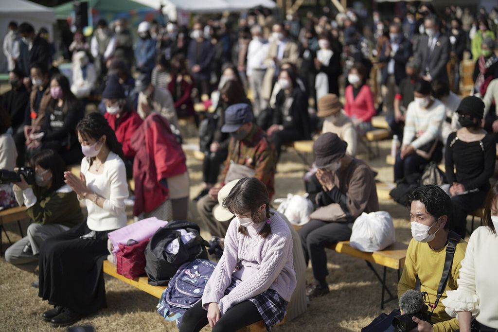Pengunjung berdoa dan mengheningkan cipta untuk para korban gempa dan tsunami 11 Maret 2011 saat acara peringatan gempa dan tsunami di Tokyo, Jepang, yang menewaskan lebih dari 18.000 orang atau hilang di Sendai, Prefektur Miyagi, Jepang, Jumat (11/3/2022). 