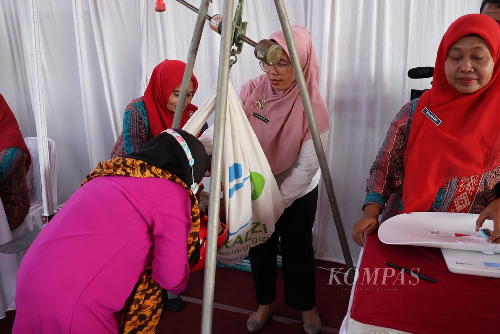 Kader Posyandu Desa Tumpatan Nibung, Kecamatan Batang Kuis, Kabupaten Deli Serdang, Sumatera Utara, mengukur berat badan anak balita, Rabu (18/10/2023).