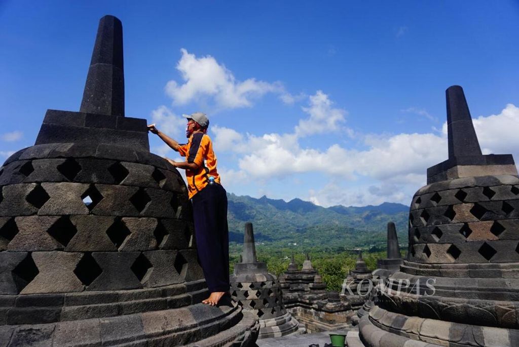 Petugas dari Balai Konservasi Borobudur (BKB), Senin (22/6/2020), membersihkan stupa Candi Borobudur dari paparan abu erupsi Gunung Merapi menggunakan kuas.