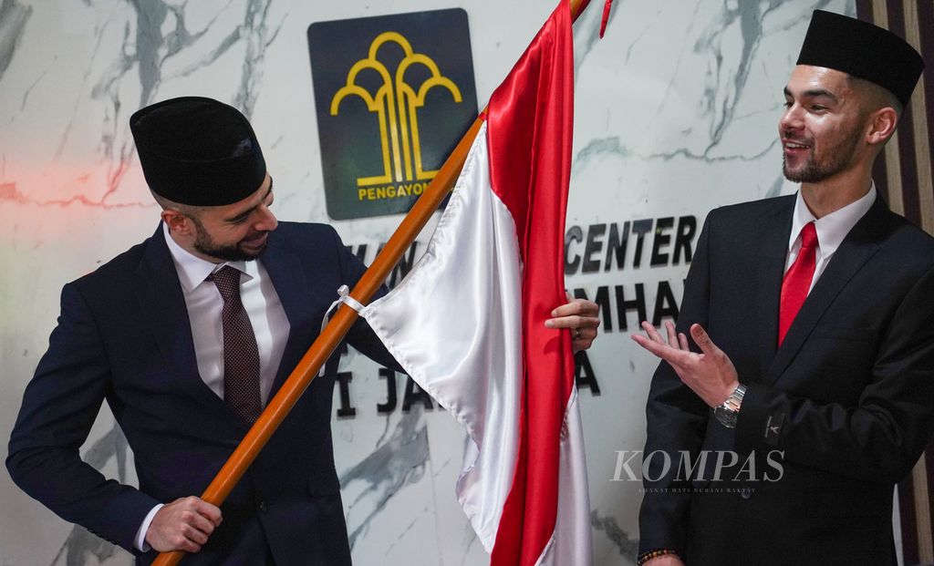 Dua pemain sepak bola naturalisasi Jordi Amat (kiri) dan Sandy Walsh memegang bendera Merah Putih seusai melakukan pengambilan sumpah janji setia sebagai warga negara Indonesia di Kantor Wilayah Kementerian Hukum dan HAM DKI Jakarta, Jakarta, Kamis (17/11/2022).