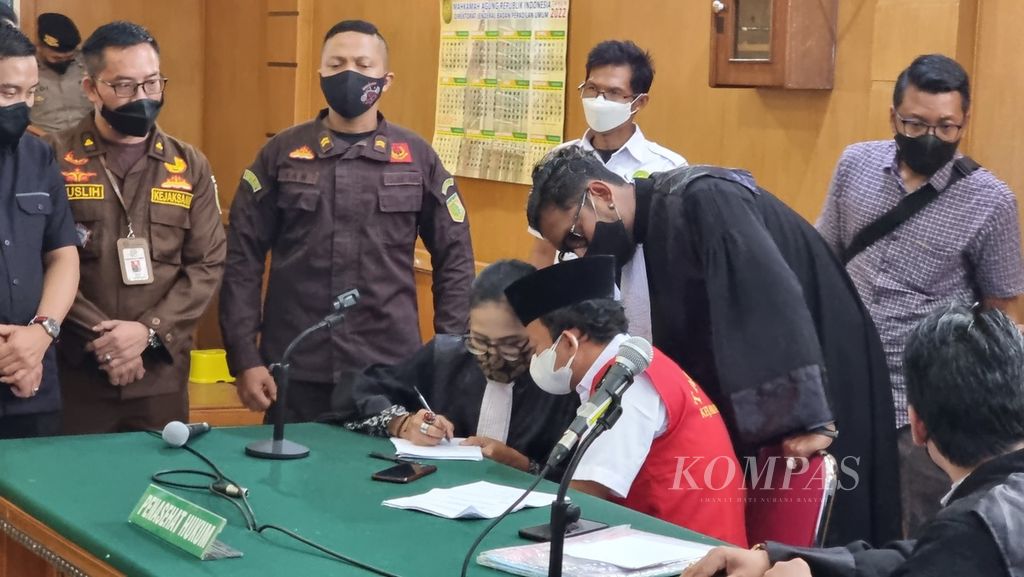 The defendant of sexual violence against dozens of students in Bandung, Herry Wirawan (red vest), discusses with his team of legal advisers in the middle of a trial at the Special Class 1A District Court in Bandung, West Java, Tuesday (15/2/2022)..