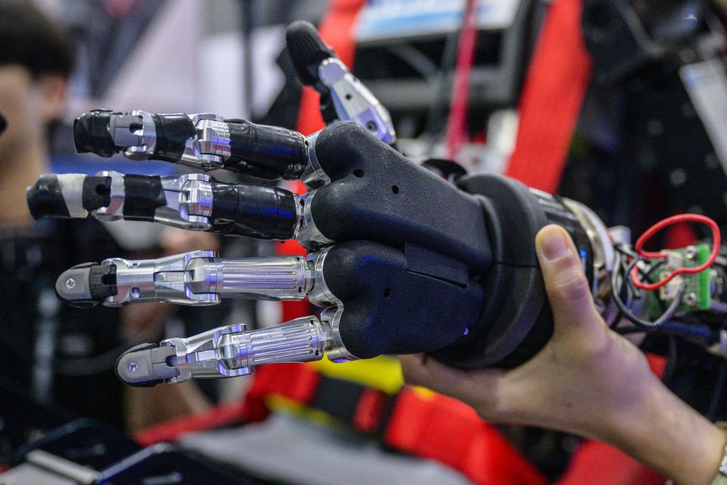 Penjaga stan mendukung tangan robot <i>humanoid </i>Pilot Robot yang diproduksi oleh KAIST Institute for Robotics (KIR), yang dipamerkan di Pameran Dirgantara dan Pertahanan Internasional Seoul (ADEX) di Seongnam, Seoul selatan, 18 Oktober 2023. 