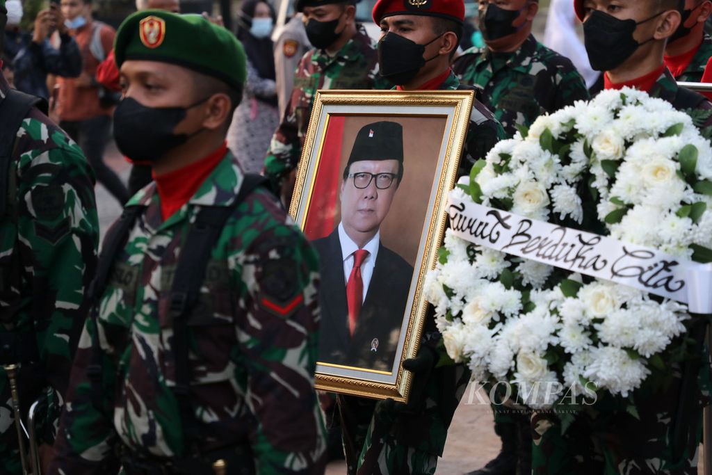 Prajurit TNI membawa foto di depan peti jenazah Menteri Pendayagunaan Aparatur Negara dan Reformasi Birokrasi (Menpan dan RB) Tjahjo Kumolo di Taman Makam Pahlawan, Kalibata, Jakarta, Jumat (1/7/2022). 