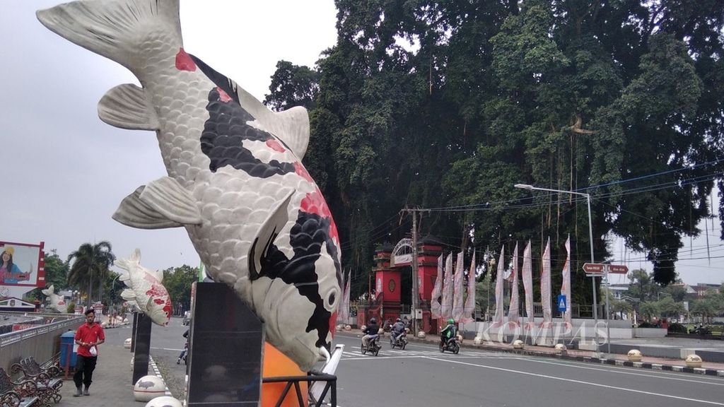 Seorang warga berjalan di trotoal yang ada di belakang patung ikan koi yang menjadi maskot Blitar, di jalan protokol Kota Blitar, Jawa Timur, 21 Desember 2021 lalu.
