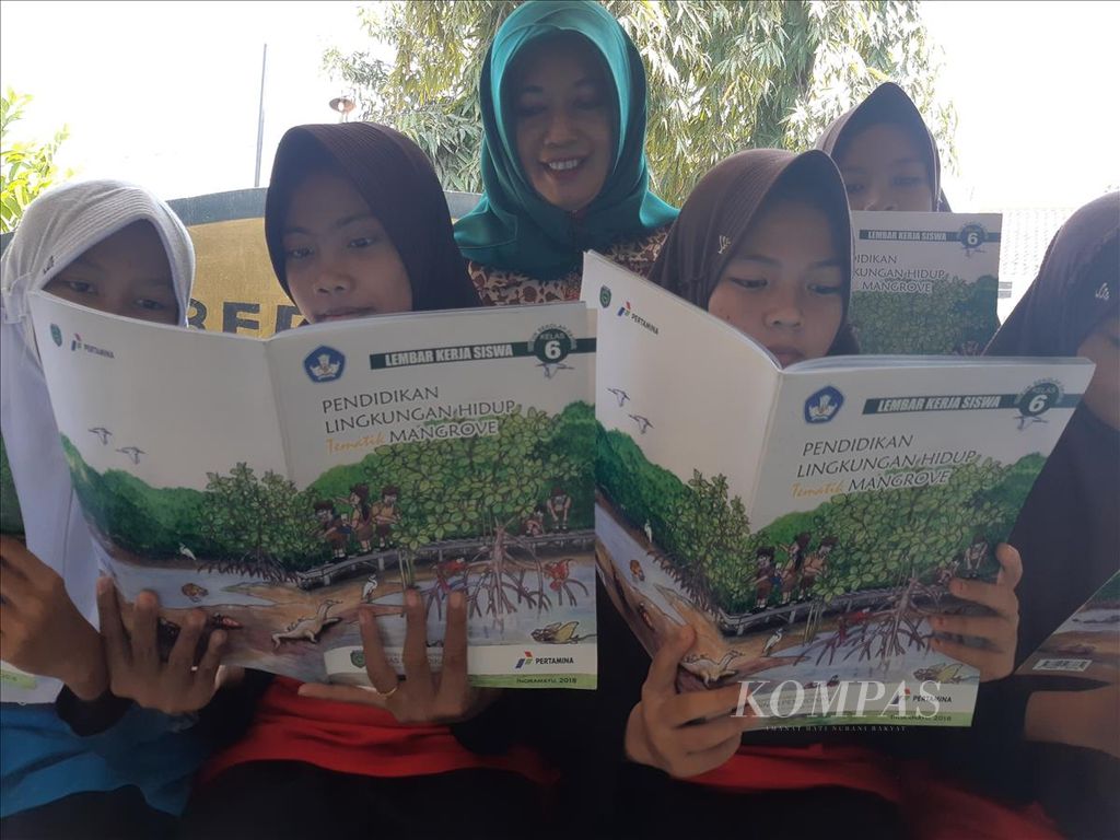 Kepala SDN Paoman IV Lutfiya bersama siswa membaca buku terkait mangrove di sekolah di Kabupaten Indramayu, Jawa Barat, Sabtu (25/5/2019). SDN Paoman IV termasuk dalam 26 SD di Indramayu yang menerapkan kurikulum pendidikan lingkungan hidup tematik mangrove. Tahun ini, ditargetkan 42 SD menerapkan hal serupa.
