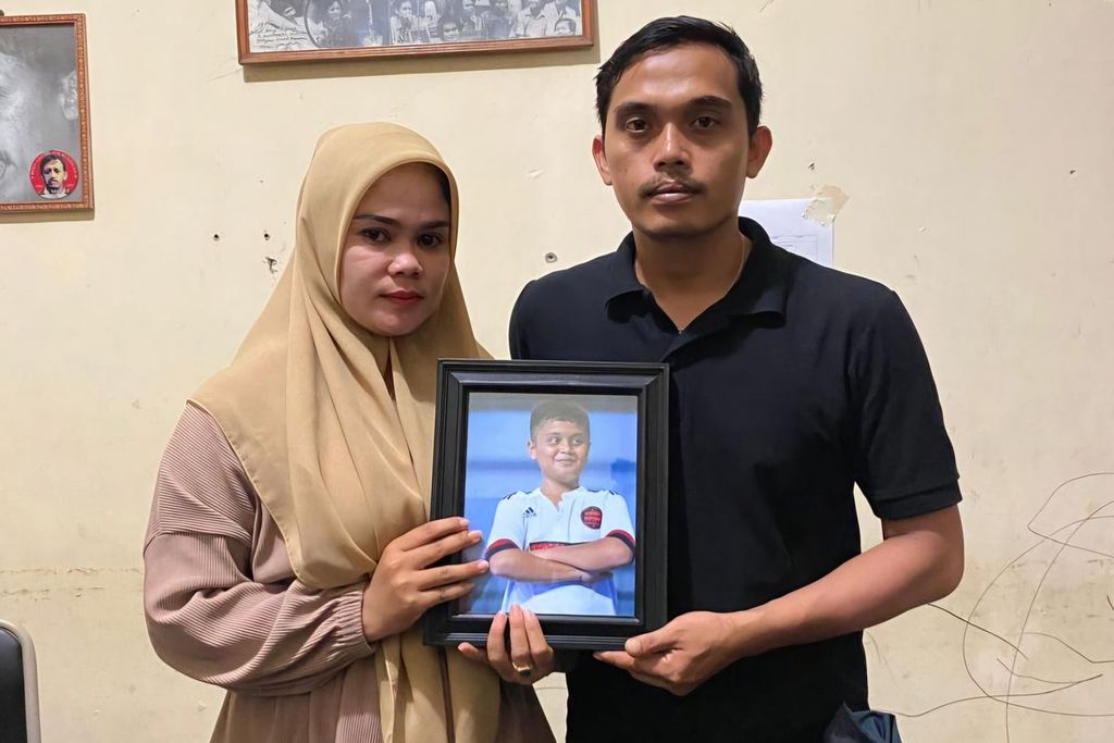 Afrinaldi (36, kanan) dan Anggun (32) berfoto dengan potret almarhum putra sulung mereka, Afif Maulana (13), di kantor LBH Padang, Kota Padang, Sumatera Barat, Kamis (20/6/2024). 