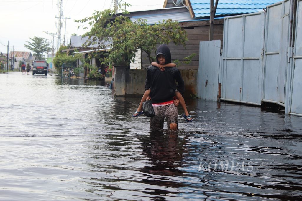 Ilustrasi. Warga Jalan Arut melintas di tengah banjir sambil menggendong anak kecil untuk menyeberang ke tempat yang lebih aman di Kota Palangkaraya, Kalteng, Kamis (17/11/2022). Setidaknya empat kecamatan di Palangkaraya terdampak banjir.