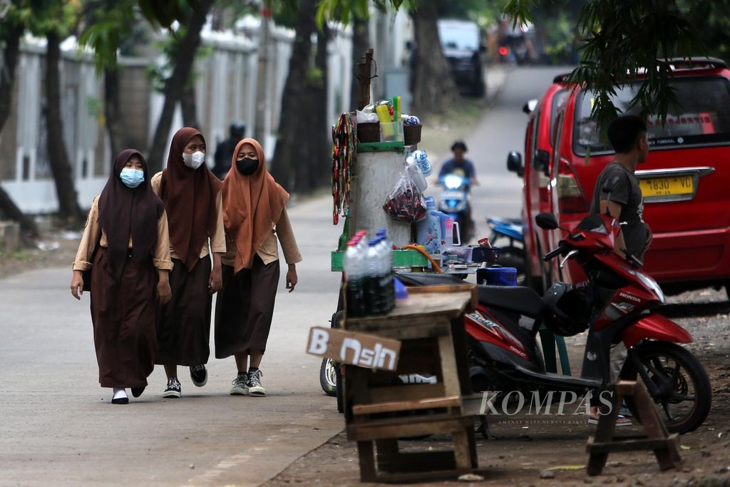 Pelajar putri melintasi jalanan di kawasan Kebayoran Lama, Jakarta Selatan, saat pulang sekolah, Rabu (30/3/2022). Pemprov DKI Jakarta akan kembali menerapkan pembelajaran tatap muka (PTM) 100 persen mulai Jumat (1/4/2022). 