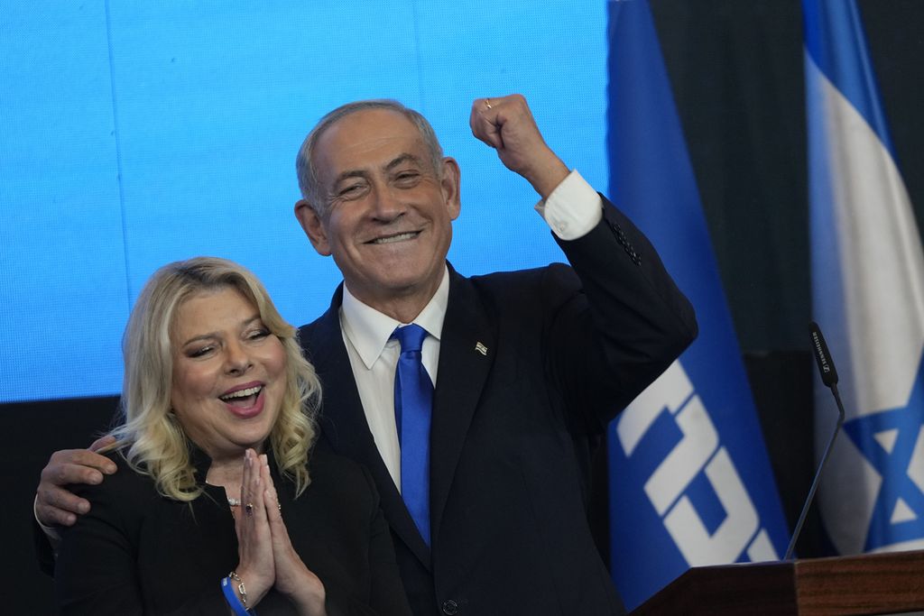 Benjamin Netanyahu, pemimpin Partai Likud, mengepalkan tangan kirinya didampingi sang istri, Sara, di hadapan pendukungnya di markas pemenangan partai di Jerussalem, Selasa (2/11/2022). Hasil jajak pendapat memperlihatkan Likud bersama sejumlah partai sayap kanan diprediksi memenangi pemilihan. Netanyahu membuka peluang untuk kembali berkuasa. 