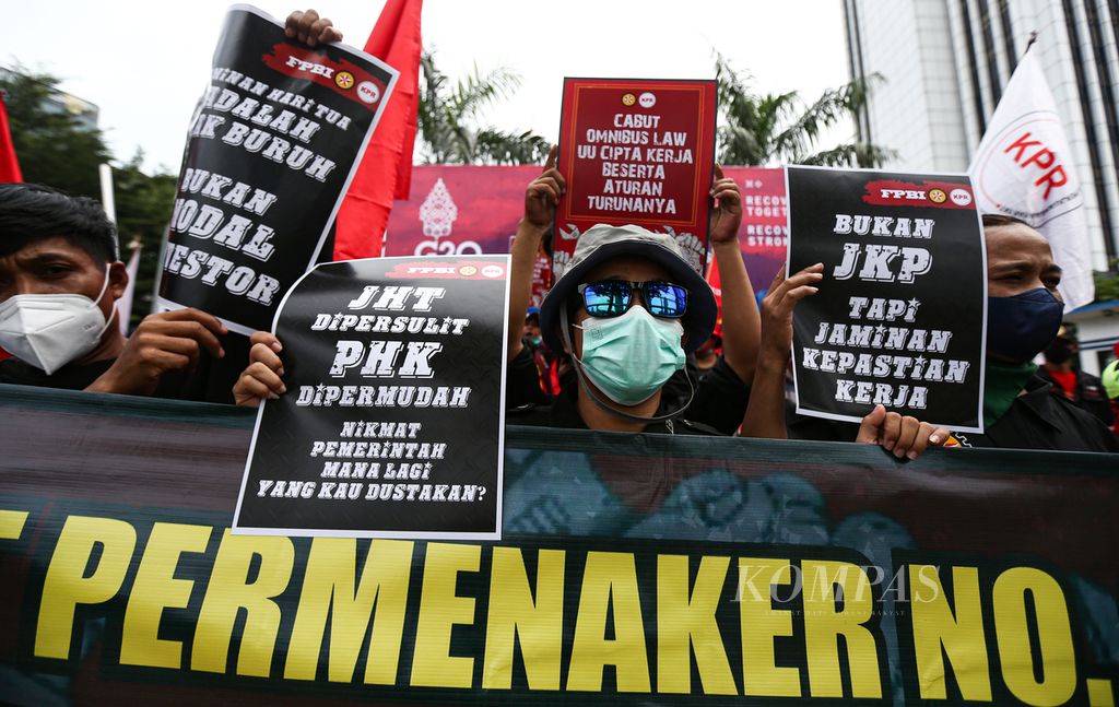 Massa buruh dari Kongres Aliansi Serikat Buruh Indonesia (KASBI) memperlihatkan poster tuntutan mereka saat berunjuk rasa di depan Kantor Kementerian Ketenagakerjaan, Jakarta, Rabu (23/2/2022).