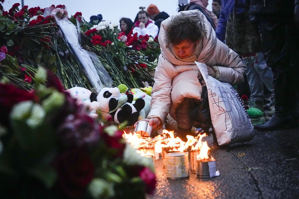 Seorang wanita menyalakan lilin di pagar sebelah Balai Kota Crocus, tepi barat Moskwa, Rusia, Sabtu, 23 Maret 2024. Badan investigasi negara Rusia mengatakan, jumlah korban tewas dalam serangan gedung konser Moskwa meningkat menjadi lebih dari 143 orang.