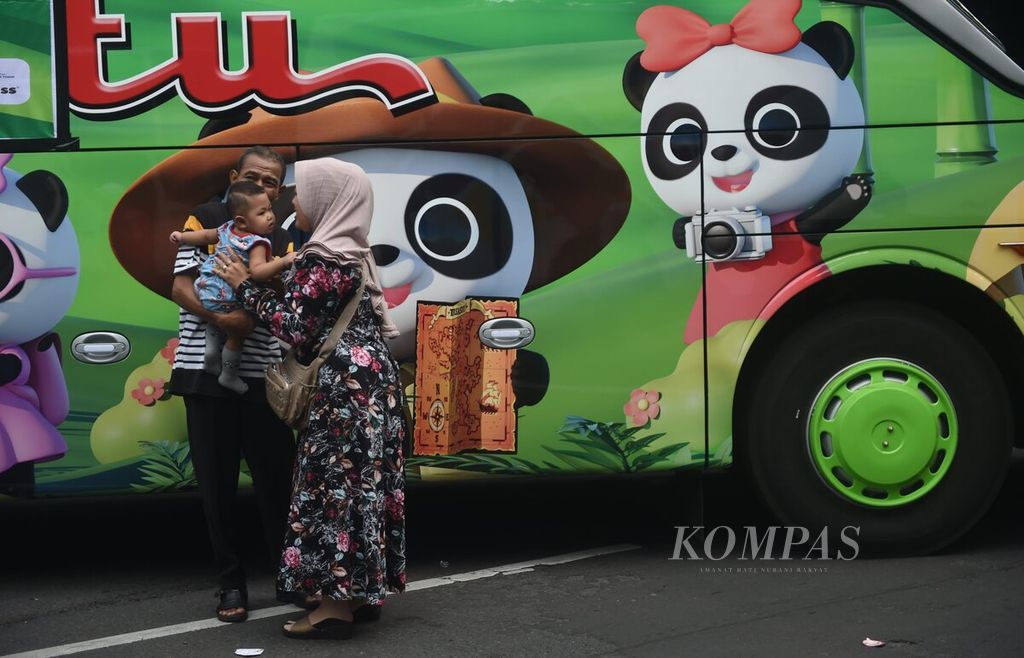 Peserta mudik bareng gratis 2024 disamping bus di depan Kantor Dinas Perhubungan Jawa Timur, Minggu (7/4/2024). 