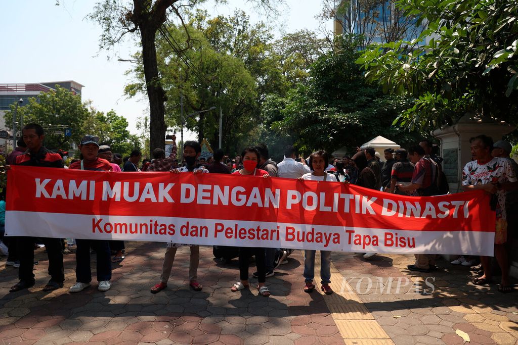 Warga membentangkan sebuah spanduk saat aksi<i> tapa bisu</i> yang digelar di depan rumah dinas Wali Kota Surakarta Gibran Rakabuming Raka di Loji Gandrung, Jalan Slamet Riyadi, Kota Surakarta, Jawa Tengah, Senin (16/10/2023).