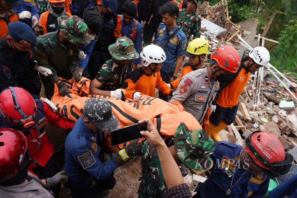 Tim gabungan SAR, TNI, polisi, dan relawan mengangkat Endah (65), warga Kampung Rawacina, Nagrak, Kecamatan Cianjur, Kabupaten Cianjur, Jawa Barat, yang ditemukan tewas tertimbun reruntuhan rumahnya akibat gempa, Rabu (23/11/2022). 