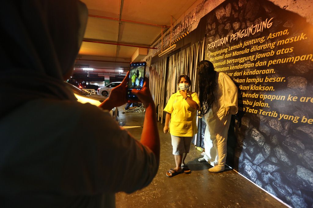 Pegawai pertokoan berfoto dengan patung kuntilanak di dekat pintu masuk wahana horor lantatur ”Terowongan Casablanca” di area parkir Mall of Indonesia, Jakarta Utara, Kamis (4/11/2021). 