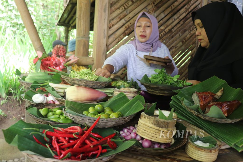 Dua anggota Komunitas Cengkeh Afo dan Rempah Gamala menata rempah dan bahan makanan yang merupakan bahan untuk pembuatan makanan tradisional di Kelurahan Tongole, Kecamatan Ternate Tengah, Kota Ternate, Maluku Utara, Selasa (29/3/2022). Komunitas tersebut menyajikan makanan tradisional kepada pengunjung atau wisatawan.
