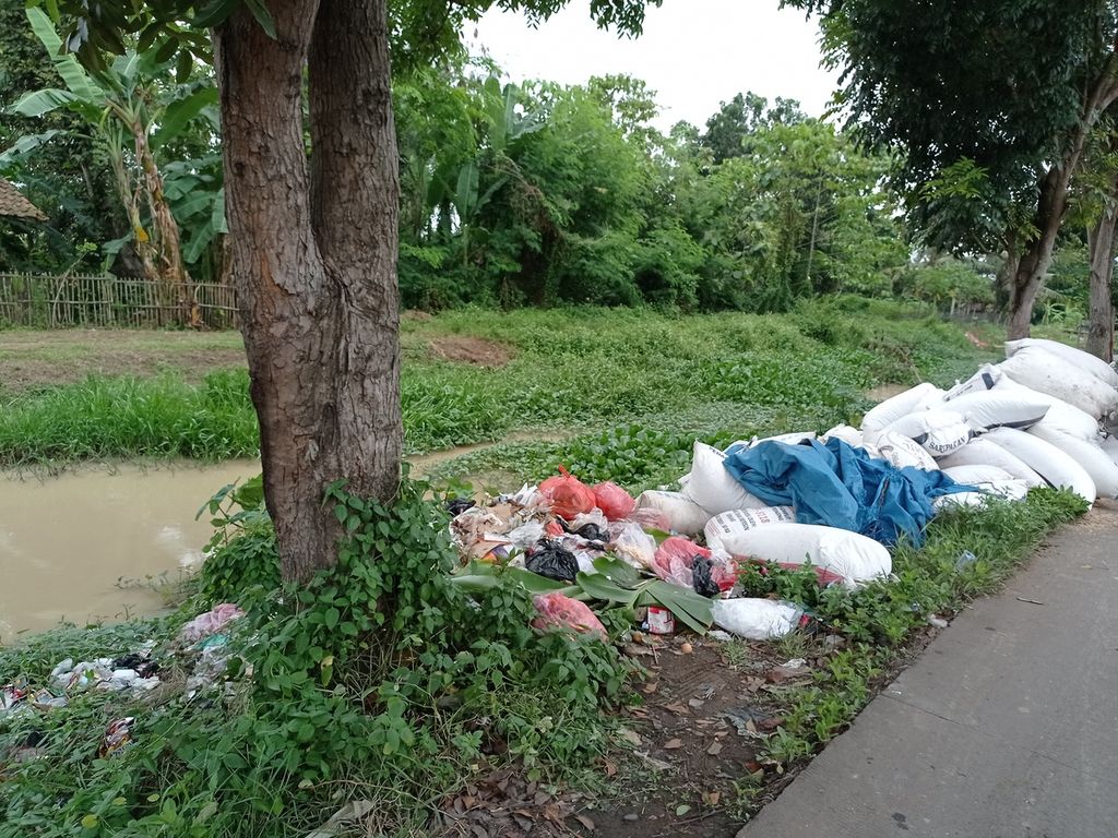 Sampah warga di Kecamatan Sukamulya, Kabupaten Tangerang, Banten, berserakan di pinggir saluran irigasi karena tak terangkut armada pengangkut sampah, Senin (8/11/2021). 