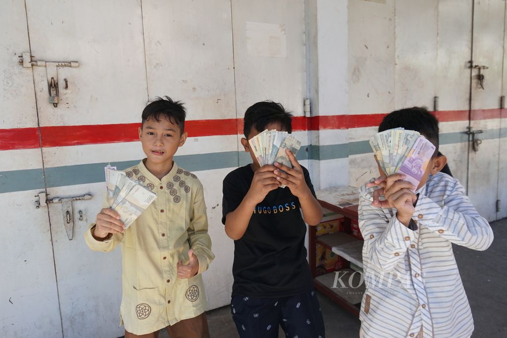 Anak-anak memamerkan uang lebaran yang mereka kumpulkan dari rumah-rumah di Kampung Arab, Manado, Sulawesi Utara, pada Hari Raya Idul Fitri 1443 Hijriah, Senin (2/5/2022). Sekalipun pintu sebagian rumah tampak tertutup rapat selepas sholat Id, warga sudah mulai saling berkunjung untuk bersilaturahmi.