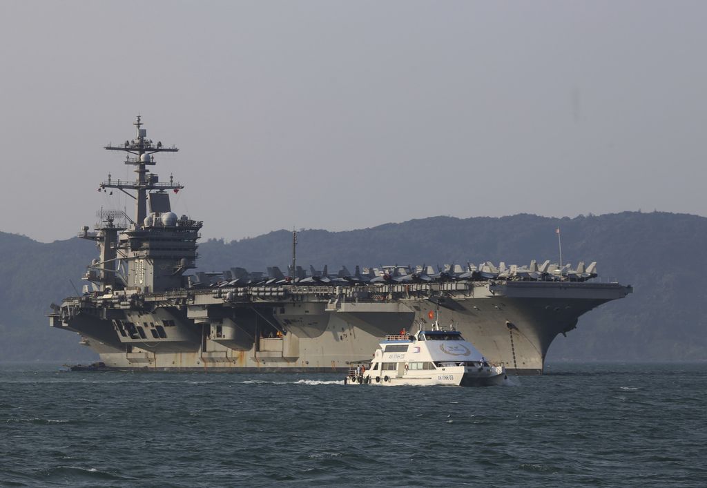 Dalam arsip foto 5 Maret 2018, kapal penumpang Vietnam berlayar melewati kapal induk AS, USS Carl Vinson, saat berlabuh di Teluk Danang, Vietnam. 