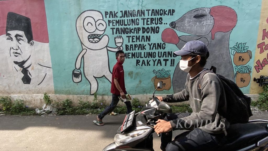 Warga melintasi mural bergambar tikus yang menjadi simbol pelaku korupsi di kawasan Cipayung, Ciputat, Tangerang Selatan, Banten, Jumat (24/9/2020). Selain untuk memperindah lingkungan, mural juga menjadi media masyarakat untuk menyampaikan harapanya kepada para penegak hukum dalam memberantas korupsi.