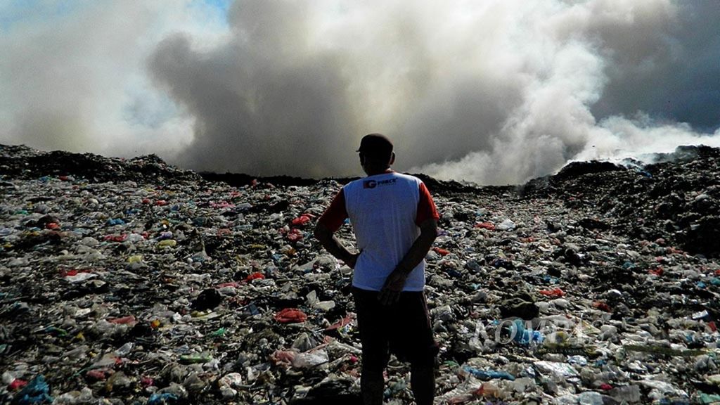 Seorang warga memandang timbunan sampah di lahan Tempat Pembuangan Akhir (TPA) Regional Sarbagita Suwung, Denpasar Selatan, Kota Denpasar, Bali. Lahan itu terbakar pada Senin (24/9/2018). Asap putih mengepul dari timbunan sampah yang terbakar.