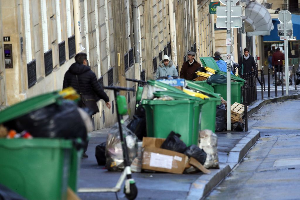Warga melintas di dekat tumpukan sampah di Paris, Perancis, 4 Februari 2020, setelah aksi mogok petugas kebersihan akibat kebijakan sistem pensiun nasional. 