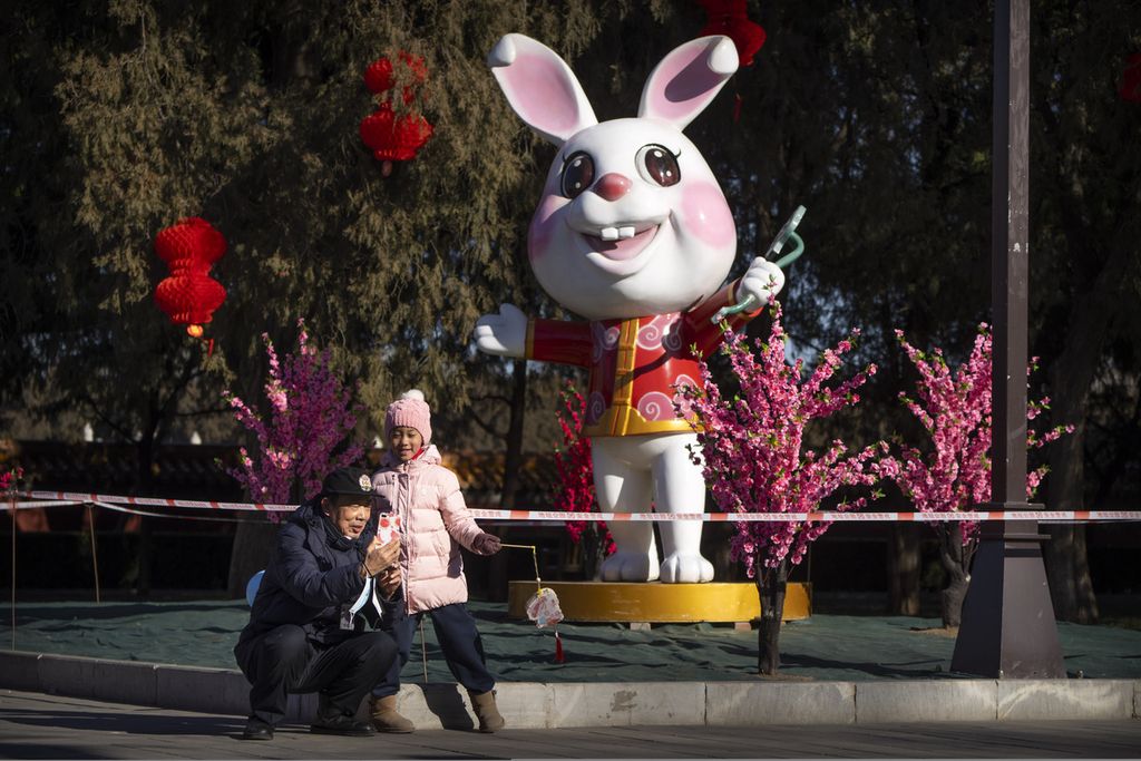 Banyak warga yang berpose <i>selfie</i> di depan patung kelinci untuk menyambut Tahun Baru Imlek di sebuah taman umum di Beijing, China, Jumat (20/1/2023). 