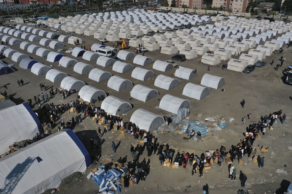 Warga korban gempa yang kini berada di tempat pengungsian mengantre untuk menerima bantuan di kamp darurat di kota Iskenderun, Turki, Selasa (14/2/2023).   