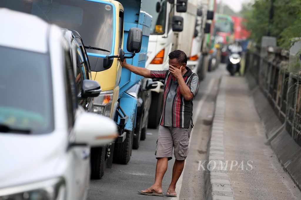 A truck driver got out of his vehicle during a traffic jam on the Marunda Access Road, Marunda, North Jakarta, Thursday (9/5/2024). The traffic jam occurred due to road repairs along about 20 meters of the road, causing vehicles to pass alternately. This caused a traffic jam of about 1 kilometer in both directions.