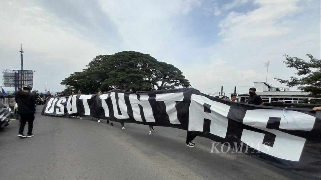 Spanduk besar bertuliskan Usut Tuntas dibentangkan oleh kelompok suporter Arema FC, Aremania, saat menggelar aksi di atas Flyover Arjosari di Kota Malang, Jawa Timur, Minggu (20/11/2022). 