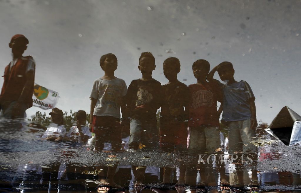 Refleksi anak-anak yang tengah menyaksikan kemeriahan kampanye Partai Republika Nusantara terlihat dari genangan air di Lapangan Pulomas, Jakarta Timur, Jumat (27/3/2009). Partai yang mengusung Sultan Hamengku Buwono X sebagai calon presiden itu menghadirkan para calon anggota legislatifnya sebagai juru kampanye. 