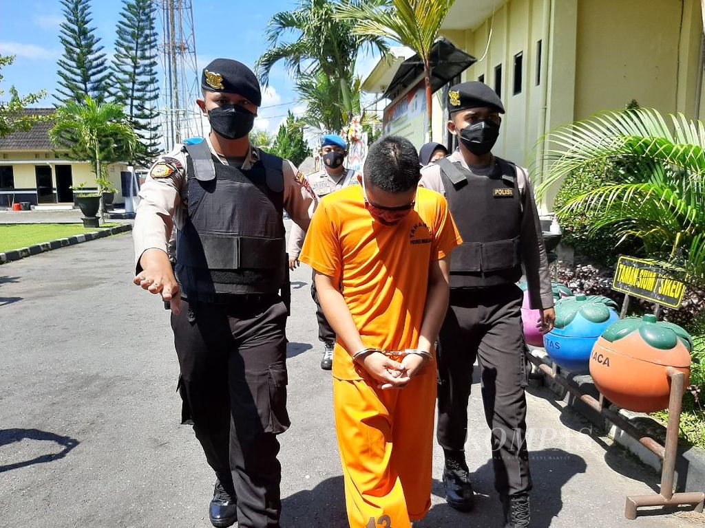 PE (22) , tersangka pencabulan terhadap anak di bawah umur, dikawal polisi untuk memberikan keterangannya di Polres Magelang, Jawa Tengah, Rabu (13/4/2022)