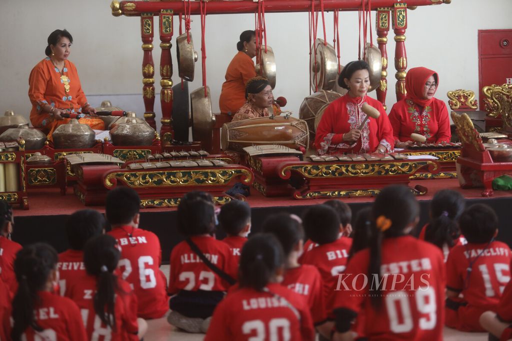 Murid-murid sekolah menikmati pertunjukan musik gamelan yang dimainkan kelompok belajar gamelan Srikandi yang rutin berlatih di Museum Nasional, Jakarta, Kamis (13/4/2023). Komunitas belajar gamelan ini rutin bermain sepekan sekali untuk menghadirkan musik tradisional gamelan kepada pengunjung museum. 