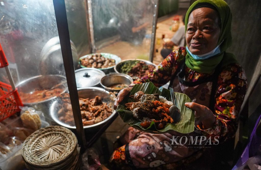 Yu Kartini (61) melayani pembeli di lesehan Gudeg Mbah Tjokro di Jalan Diponegoro, Kota Yogyakarta, DIY, Selasa (6/9/2022). Makanan khas Gudeg hingga kini masih menjadi pilihan favorit santapan bagi masyarakat lokal maupun pelancong yang datang ke Yogyakarta. Yu Kartini berjualan gudeg sejak tahun 1987. KOMPAS/RONY ARIYANTO NUGROHO 25-9-2022