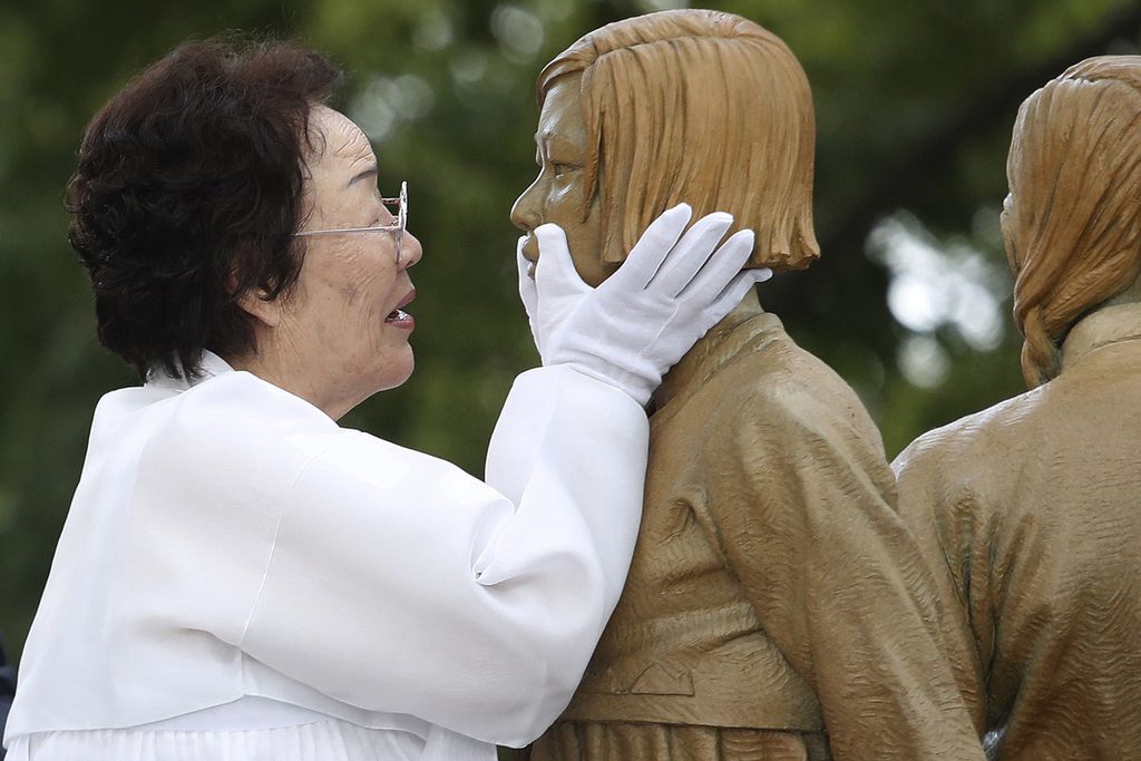 Dalam arsip foto 14 Agustus 2019 ini, Lee Yong-soo, yang dipaksa menjadi budak seks selama Perang Dunia II, menyentuh wajah patung seorang gadis yang melambangkan masalah masa perang perempuan penghibur" saat upacara pembukaannya di Seoul, Korea Selatan. 