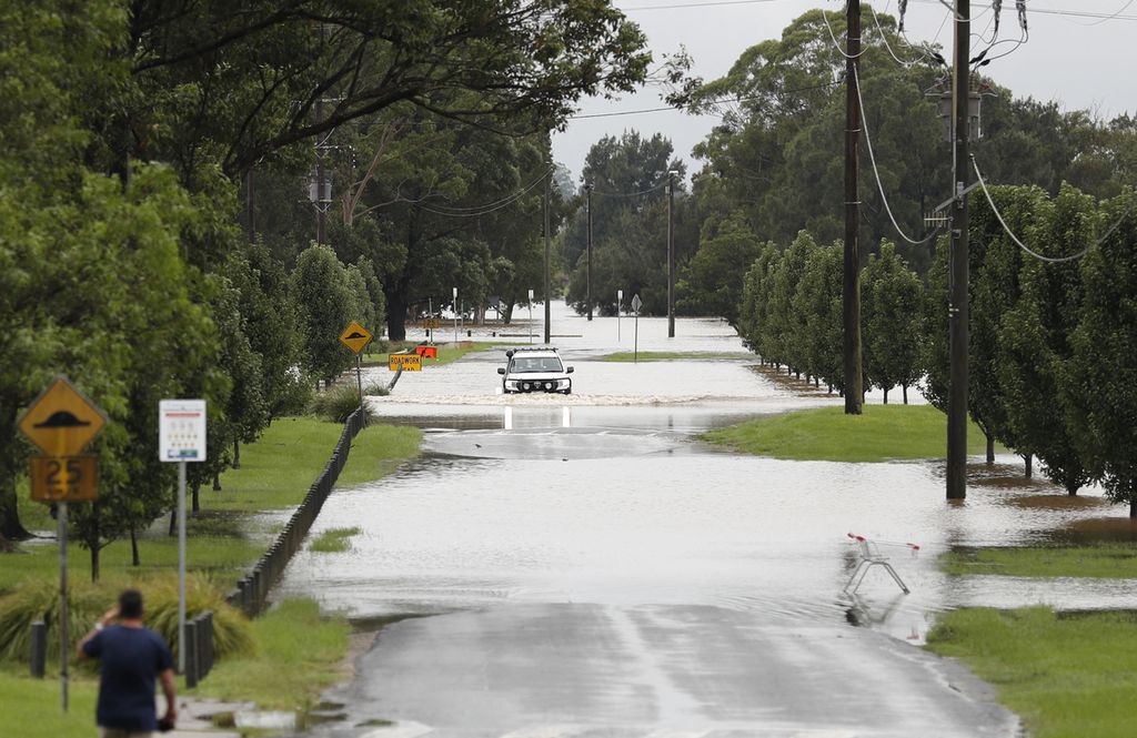 Sebuah mobil melewati banjir yang meninggi di sepanjang Hawkesbury River di Sydney, Kamis (3/3/2022).
